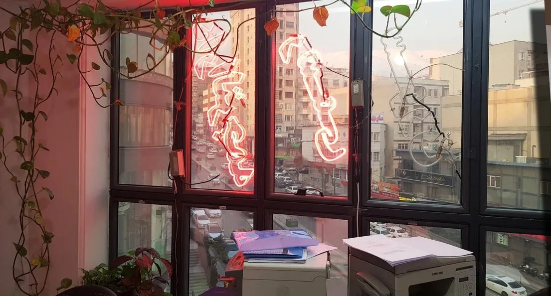 پنجرهٔ دفتر سورن با تابلوی نئون نام دفتر